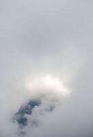 plane flying through a cloudy sky with a mountain in the background photo