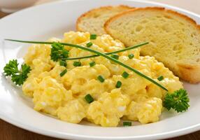 A plate of scrambled eggs and toast on a table photo