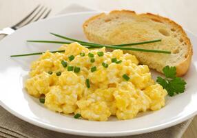 Scrambled eggs with toast on a white plate photo