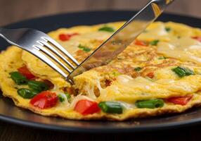 A fork is cutting into an omelet on a plate photo