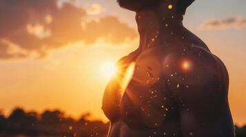 A muscular man's torso is backlit by the radiant sunset, evoking power and serenity. photo
