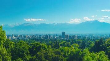 Cityscape nestled among lush green trees, with mountains and bright blue sky in the background. photo