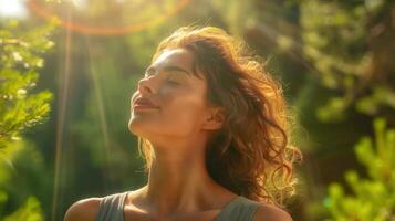 A serene woman enjoys the sun's warmth, breathing in the fresh air amidst a green forest. photo