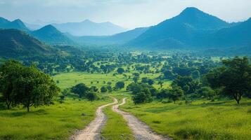 A winding road meanders through a beautiful green valley, framed by scenic hills and mountains. photo