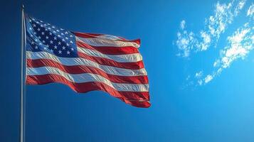 The American flag waving proudly in the wind with a bright blue sky in the background. photo