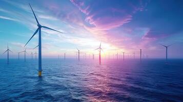 Wind turbines generate clean energy in the ocean as the sun sets with beautiful colors in the sky. photo