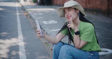 Handheld shot, Cheerful young woman happily takes a selfie while sitting on the sidewalk. video