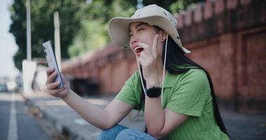 Handheld selective focus shot, Cheerful young woman happily takes a selfie while sitting on the sidewalk. video