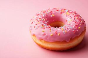 A pink donut with sprinkles on a pink background photo