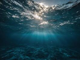 Sunlight Filtering Through the Deep Blue Ocean Depths Creating Ethereal Underwater Scenery with Ripples and Sea Floor Texture Underneath the Azure Surface photo