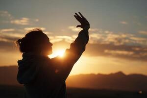 A woman raising her hands in the air at sunset photo