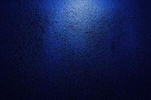 A dark blue wall with a light shining on it photo