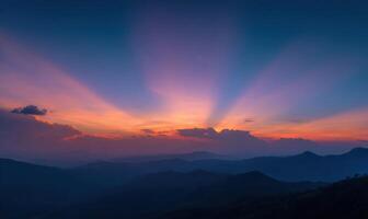 Sunset over mountains with sun rays shining through photo