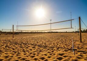 A volleyball net on a sandy beach with the sun shining photo