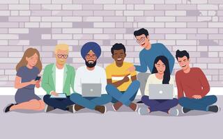 People of diverse backgrounds casually sitting with laptops and a phone in front of a brick wall. Teamwork, modern lifestyle vector