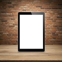 Tablet pc with blank screen on wooden table with brick wall background photo