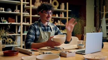 Caucasian guy man student online class pottery workshop male blogger craftsman artist designer potter teacher showing handmade bowl modeling clay teach craft ceramics call tutorial lesson laptop video