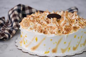Toasted Lemon Meringue Layer Cake featuring moist cake layers with a tangy lemon filling with napkin isolated on grey background side view of stunning dessert photo