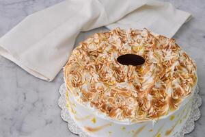 Toasted Lemon Meringue Layer Cake featuring moist cake layers with a tangy lemon filling with napkin isolated on grey background top view of stunning dessert photo