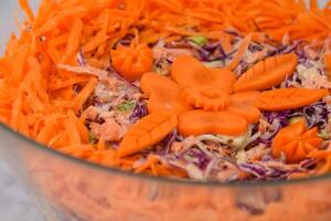 Colorful Carrot and Cabbage Coleslaw Salad in a glass bowl featuring shredded green and red cabbage with a creamy sauce, topped with shredded bright orange carrots closeup view of classic salad photo