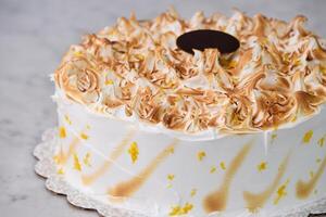 Toasted Lemon Meringue Layer Cake featuring moist cake layers with a tangy lemon filling isolated on grey background close side view of stunning dessert photo