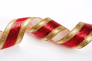 A vibrant red and gold curled ribbon elegantly spirals on a pristine white backdrop, embodying festive charm and sophistication. photo