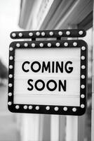 Vintage marquee sign with bright bulbs displaying the phrase Coming Soon, creating an inviting atmosphere for upcoming events or announcements in a stylish setting photo