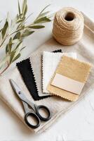 Fabric swatches in various colors, scissors, and twine arranged on a neutral background, showcasing textile selection and crafting materials for creative projects photo