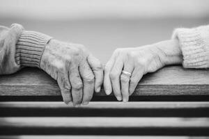 Elderly couple's hands gently clasped together on a wooden railing, showcasing love and connection, with a soft focus background emphasizing intimacy and warmth photo