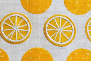 Bright yellow embroidered fabric featuring circular lemon designs and polka dots, showcasing intricate stitching and vibrant colors, perfect for textile and design projects photo