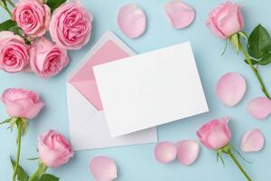 Pink roses arranged around a blank white envelope on a soft blue background, with scattered rose petals creating a romantic and elegant atmosphere for invitations or greetings photo