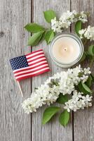 American flag, white flowers, and a lit candle arranged on rustic wooden surface, creating a serene and respectful atmosphere for Memorial Day remembrance and reflection photo