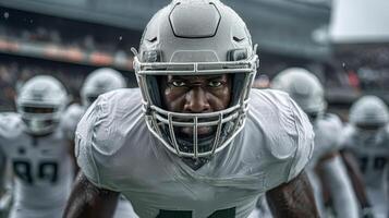 A black football player in a white uniform and helmet stands in the center of the field photo