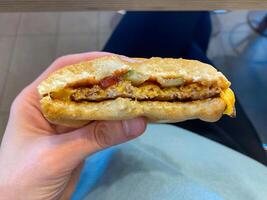 A bitten off cheeseburger in a man's hand, a child enjoying a tasty hamburger photo