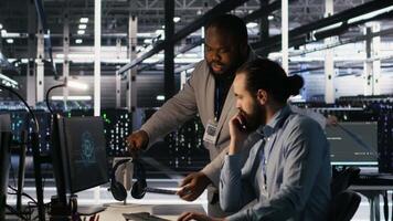 Data center engineers use laptop, collaborating on doing AI software updates. Server room teamworking colleagues doing brainstorming, optimizing infrastructure using artificial intelligence, camera A video