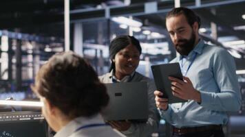Data scientists working together in server room, reviewing neural network code and LLM visualization dashboards. Team of IT experts coordinating tasks, monitoring AI system performance, camera A video