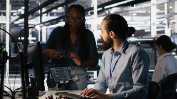 Teamworking system administrators in data center integrating AI automation during maintenance session. Server farm coworkers configuring machine learning models across equipment rigs, camera A video