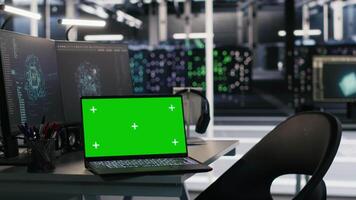 Chroma key notebook and PCs in high tech data center workspace used for AI system monitoring and performance tracking. Mockup notebook overseeing server racks involved in computing operations video