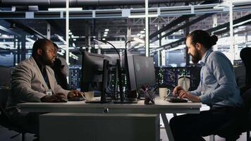 Panicked engineers in data center react to ransomware warning on PC display, scrambling to launch emergency response protocol. IT staff urgently trying to fix hacked infrastructure systems, camera A video