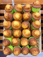 Freshly made cupcakes are laid out in a row on the counter in the store, vertical picture photo