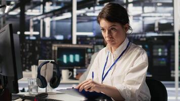 Server room admin holding clipboard, following procedures to evaluate system performance metrics. Data center employee going over maintenance fixes list, running diagnostics on equipment, camera A video