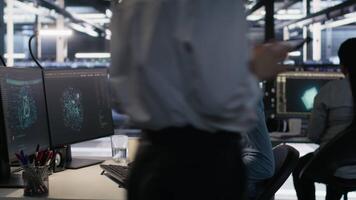 Data center system administrator talking with coworker in office while doing software updates. Server room IT expert and colleague chatting, optimizing infrastructure rackmounts configuration, camera A video