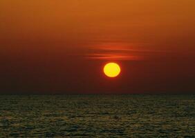 A large orange sun is seen in the sky photo