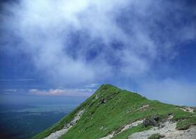 a view of the summit of a mountain with clouds in the sky photo