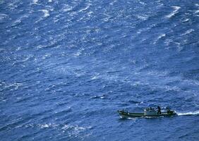 A small boat in the middle of the ocean photo