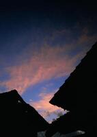 A sunset over a village with some roofs and a sky photo