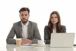 Two business professionals sitting at a desk with laptops and coffee photo