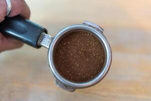 Hands holding espresso portafilter with ground coffee, ready for making the first sho photo