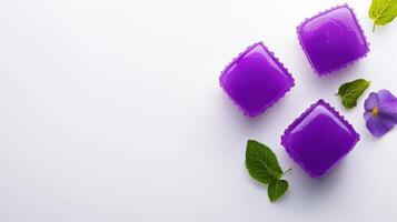 Three purple jelly candies with leaves on a white surface photo
