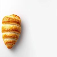 A croissant is shown on a white surface photo
